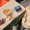 Blue JBL GO3 Bluetooth speaker lying on a container along with some snacks